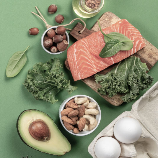 Assortment of vegetables, proteins, nuts and herbs utilized in medical weight loss: eggs, avocado, salmon, basil, olive oil, almonds and cashews.