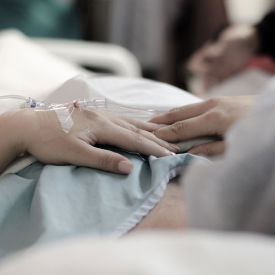 Patient holding hand with family member in hospital