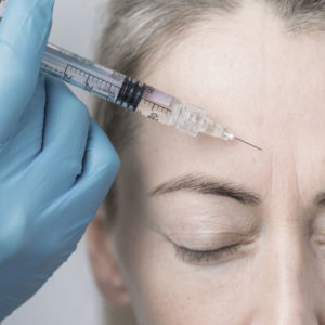Woman receiving botox facial from doctor