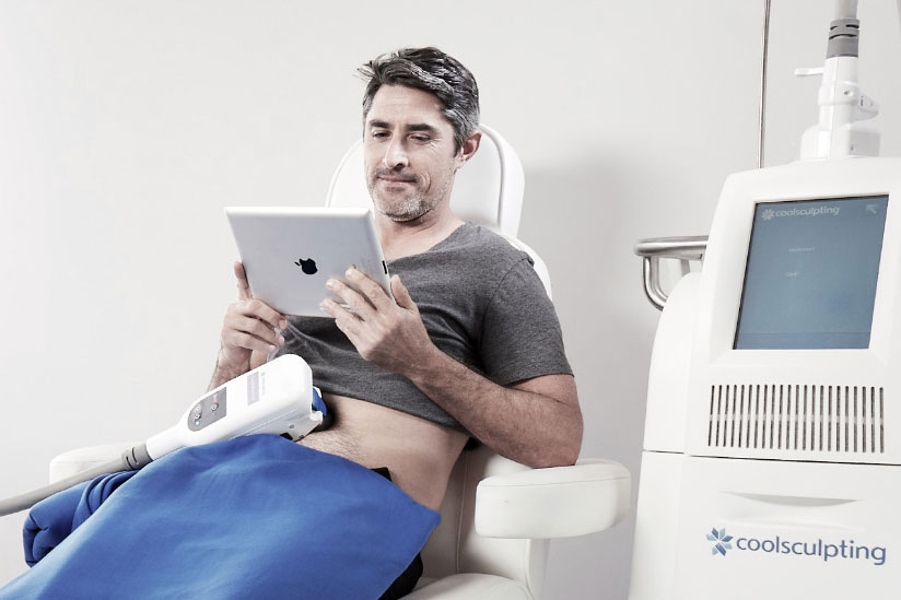 Man watching ipad receiving medical spa body contouring treatment